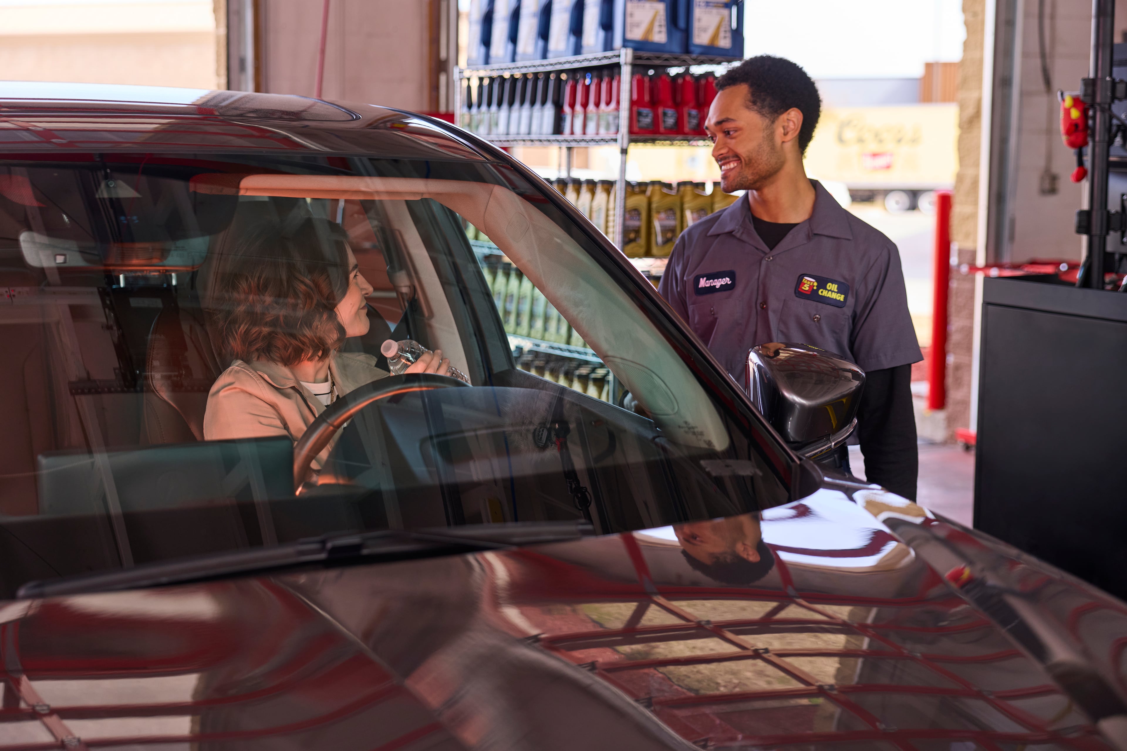 A Take 5 technician greets a driver in the service bay with a bottle of water.