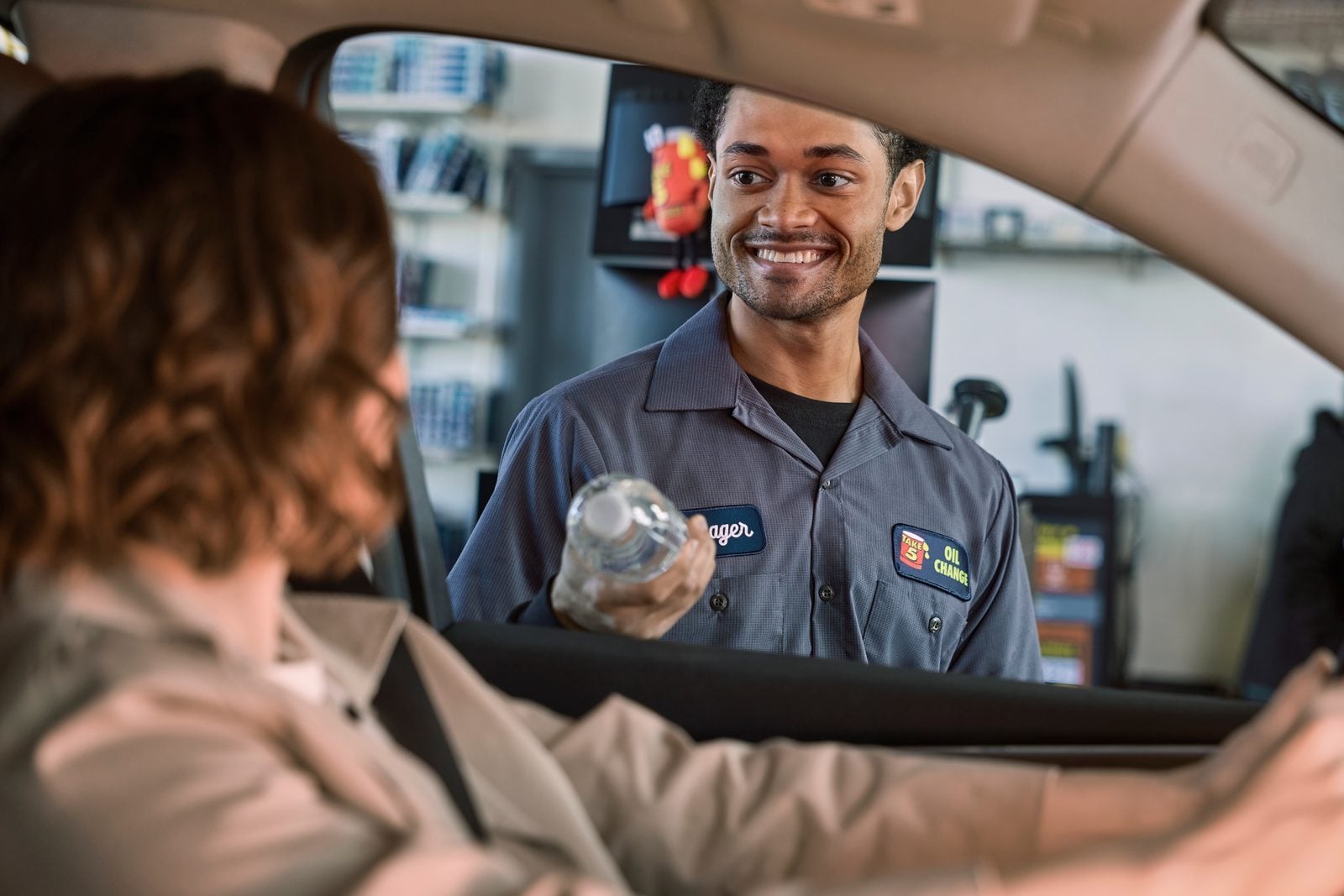 Un técnico de Take 5 da servicio a un vehículo mientras el conductor permanece en el carro