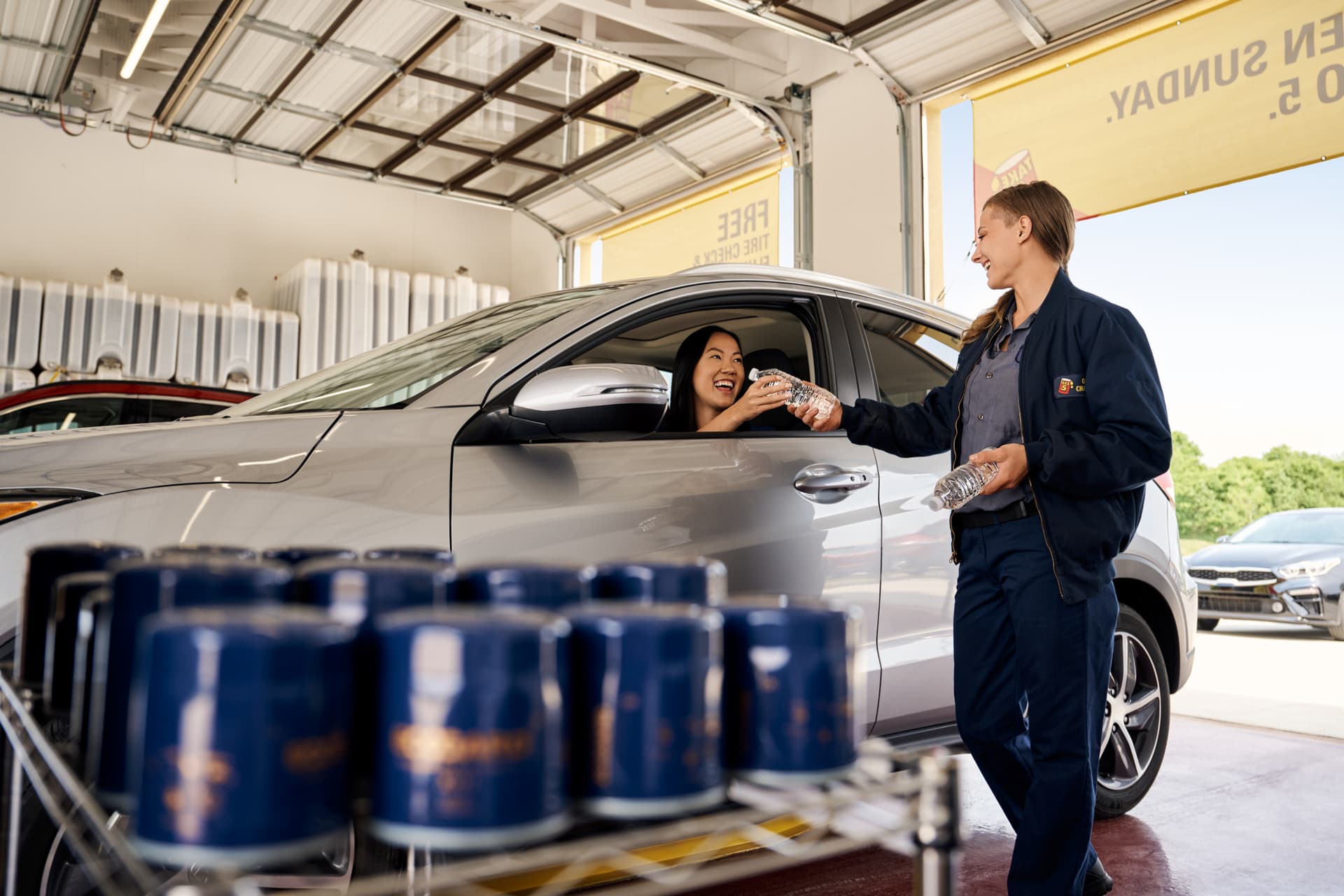 Technician greeting a customer with a water bottle at Take 5 Oil Change